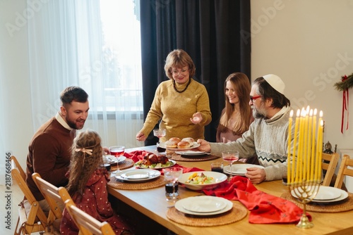 Foto Jewish family celebrating hanukkah holiday at home dinner