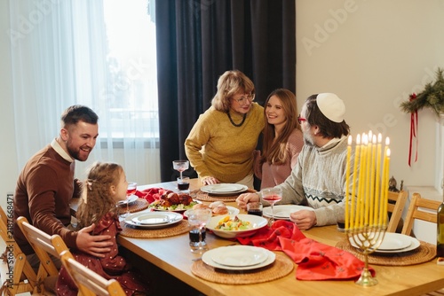 Family celebrating hanukkah with menorah candles lit