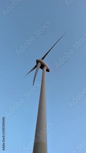 a vertical shot of wind turbine against the blue sky