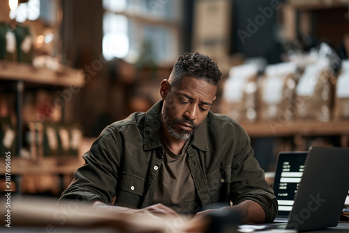 Middle-aged black man working on a laptop and taking notes in a cafe  