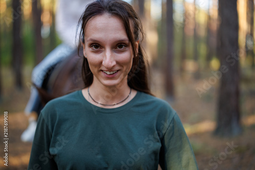 Portrait of a young woman in a green T-shirt smiling in a pine forest