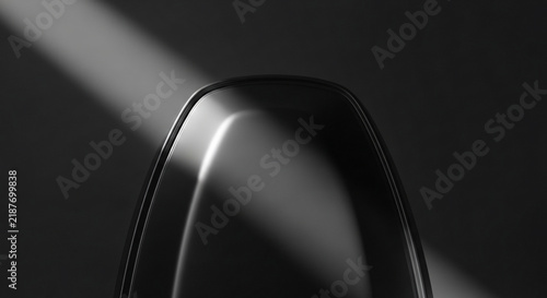 Abstract closeup of a sleek, modern black object with smooth curves and dramatic lighting against a dark background