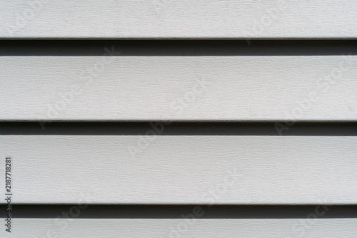 Close view of rows of old green vinyl siding in the sun.