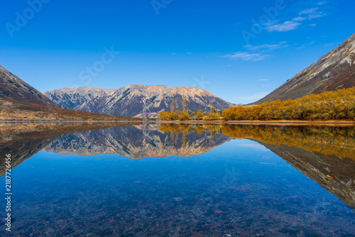 Bild auf Leinwand Autumn willows and a scree mountain range mirrored in a clear alpine lake, New Z