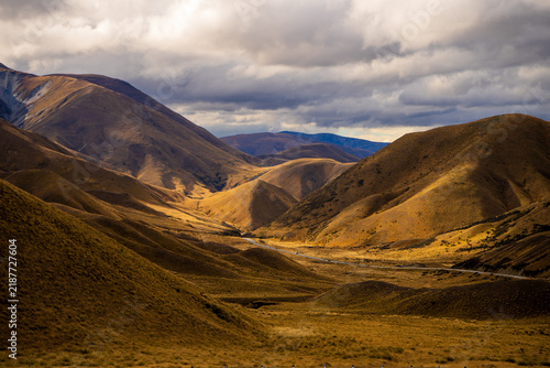 фотографія Golden tussock hills and a winding highway through a high mountain pass, New Zea