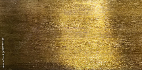 Shiny brushed gold metallic foil texture background with horizontal shimmer reflection