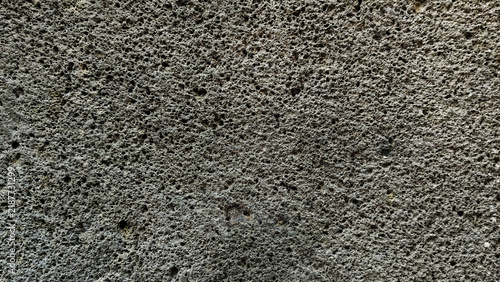 Dark grey porous volcanic basalt rock texture background