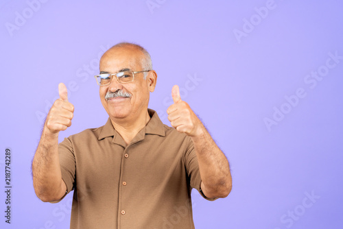 Senior man smiling, showing double thumbs up sign