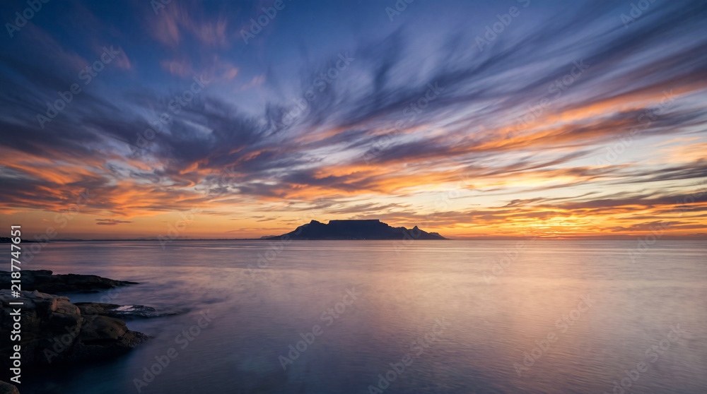 Fototapeta premium Table Mountain silhouette at sunset over the calm ocean