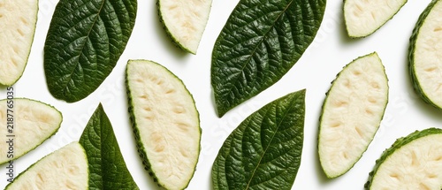 Collection of pressed soursop slices and leathery green leaves, pure white background