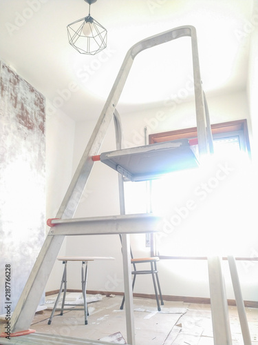 Foto A metal stepladder stands in a bright room undergoing renovation, bathed in warm sunlight