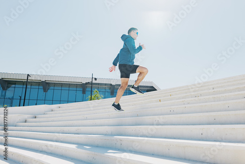 Cuadro en lienzo Young man energetically running up outdoor steps in bright sunlight