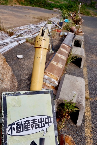 Plakat 不動産売出中の看板。物が散乱した乱雑な土地の一角