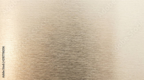 Brushed champagne metal sheet macro texture with warm neutral tones and fine horizontal grain, creating elegant industrial background for design