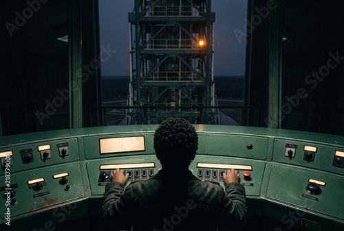 Launch control operator in a dark industrial command center at night