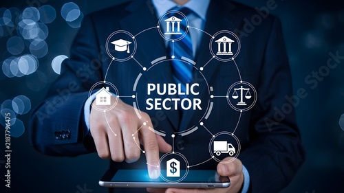 Public sector management and government services concept. Businessman touching tablet screen with digital interface showing public sector icons for administration and civil service. Professional 