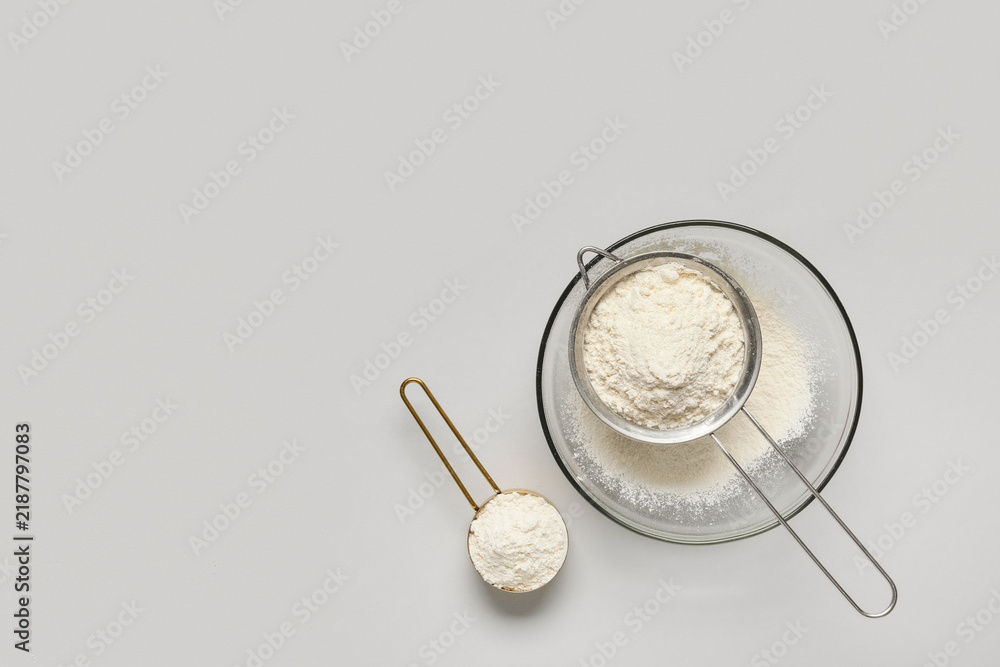 Obraz premium Baking and culinary preparation, wheat flour in a sieve and measuring cup for cooking recipes and homemade food production on a neutral background