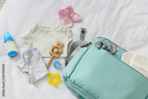 Baby bag with accessories and toys on bed, top view