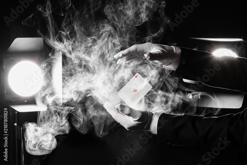 Quadro su tela Male magicians hands with levitating playing card and smoke against glowing ligh