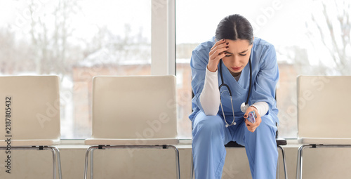 Healthcare burnout and medical professional stress, exhausted nurse sitting i...