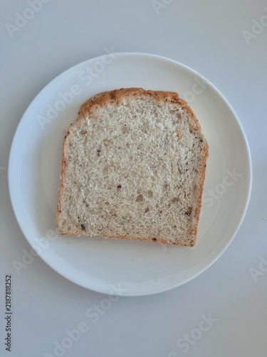 Bild auf Leinwand Single slice of multigrain bread on a white plate with copy space