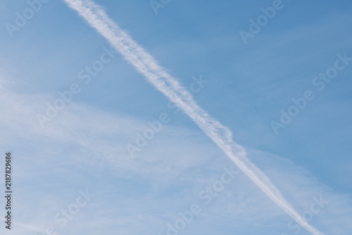 Foto Sky with a single contrail crossing a blue, clouded expanse