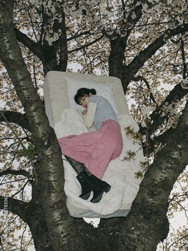 Obraz na płótnie 桜の木の上に置かれたマットレスで眠る女性