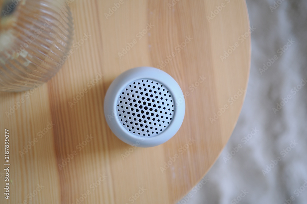 Obraz premium Small speaker on wooden table with glass nearby