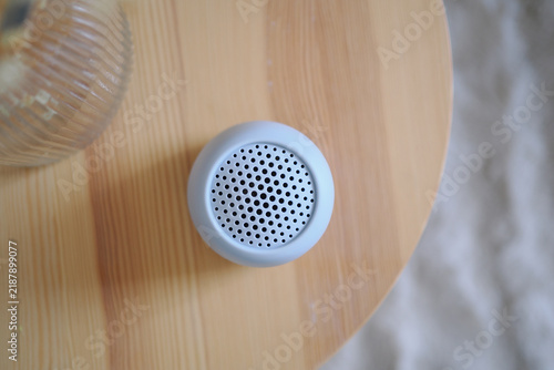 Small speaker on wooden table with glass nearby