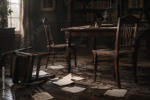 Two wooden chairs pulled apart at a table, one overturned with scattered papers.