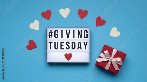 Giving Tuesday lightbox sign with red and white hearts and a wrapped gift box on a blue background