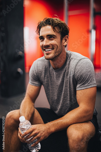 Athletic Man Resting and Holding Water Bottle During Gym Workout Session