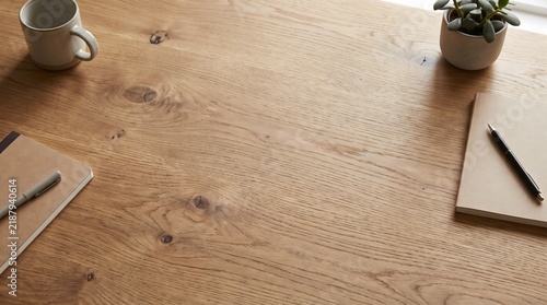 Top down view empty rustic wooden desk surface with coffee cup, pen, and notepad