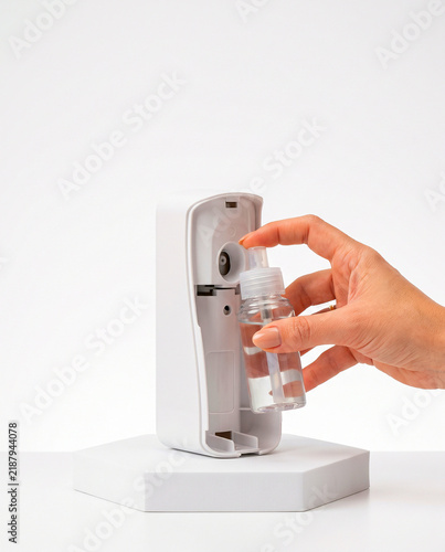 Hand Refilling Automatic Air Freshener Spray Dispenser on White Podium
