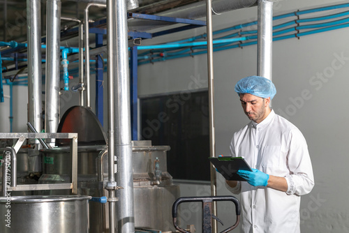 Industry inspector QC worker checking machine operation for safety and hygienic standard in food and drink factory.