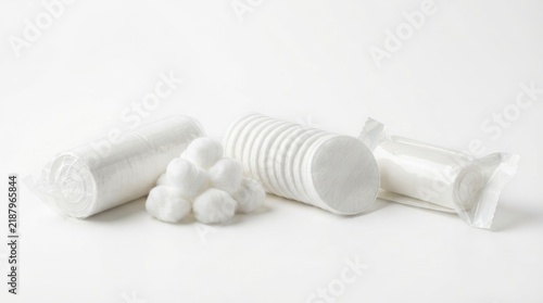 Medical dressing supplies including gauze rolls, cotton balls, and round cotton pads isolated on white background