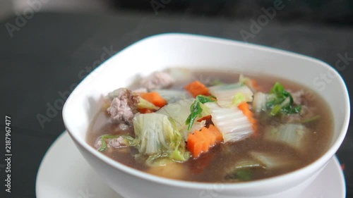 4K Delicious hot vegetable soup with minced pork carrots and Chinese cabbage served in white bowl, representing healthy Asian comfort food and home cooking concept.