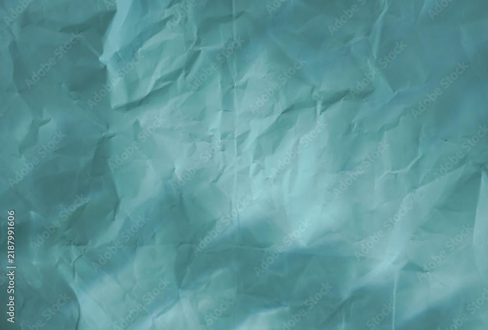 Obraz premium Crumpled light blue turquoise paper texture with soft light reflection, ideal as an abstract backdrop or graphic element for design projects.