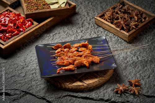 фотографія spicy barbecue meat skewers on black plate with seasoning ingredients