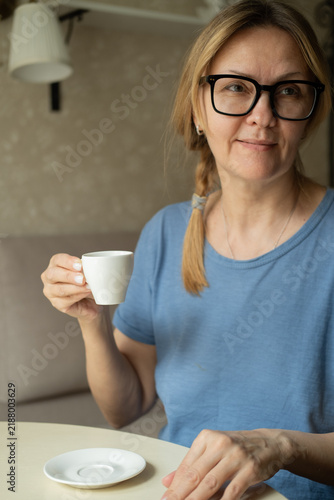 Quadro su tela Happy dreamy middle aged woman is staying in living room with cup of black tea or coffee, looking away, Peaceful mature lady enjoying no stress calm positive pastime alone at home
