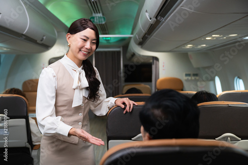 Flight attendant welcoming female passenger inside airplane cabin
