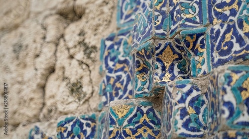 Ancient blue and yellow mosaic tiles on stone wall