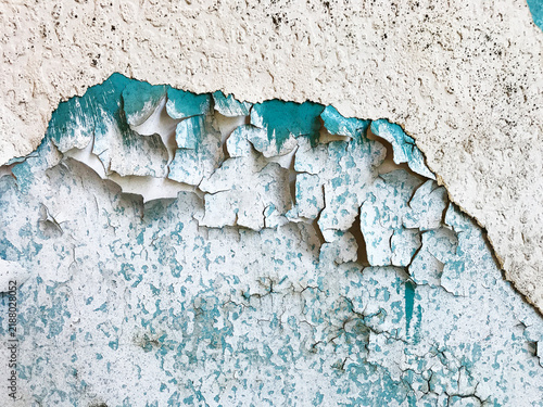 Layers of cracked paint peeling and decaying on a textured exterior stone wall