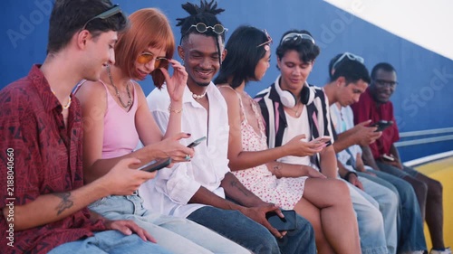 Diverse group of young friends using smartphones together outdoors