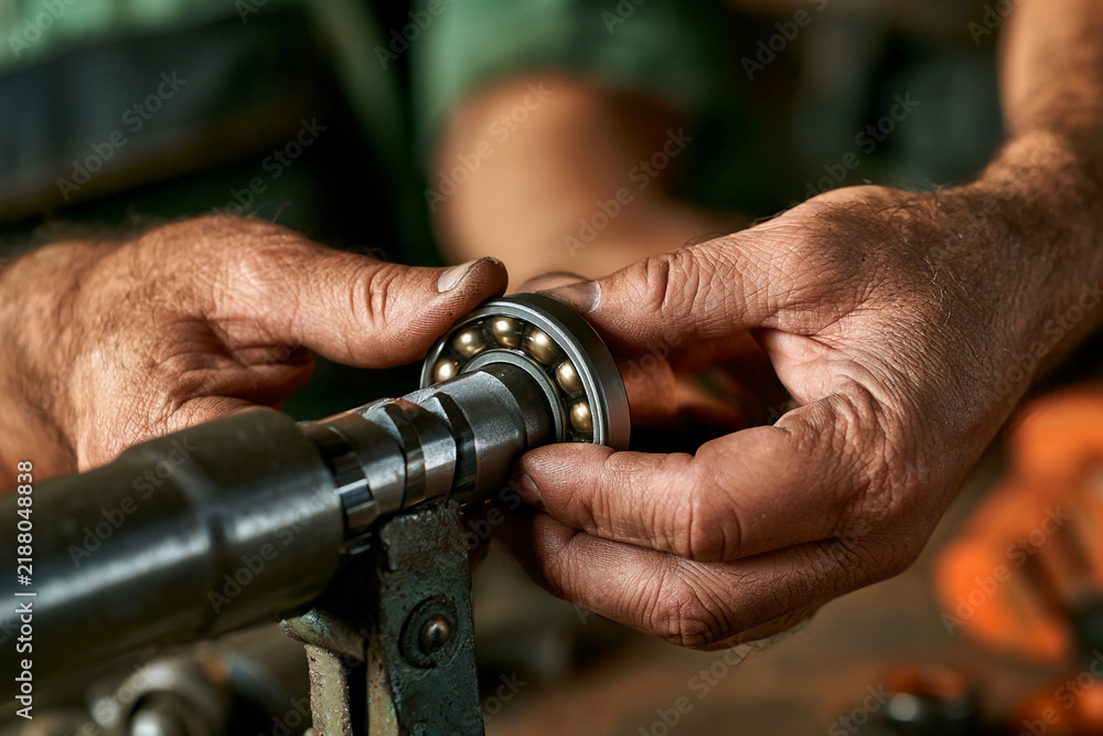 Fototapeta premium Hands work on a machine part in a workshop during daytime