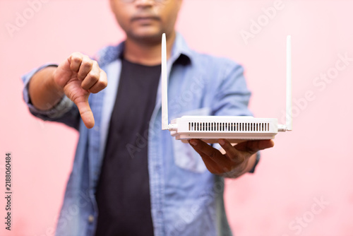 Foto Man Holding Wi-Fi Router and Giving Thumbs Down for Wireless Internet Connectivi