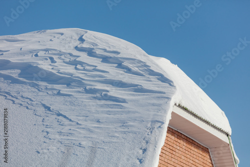 Принти на полотні Snow blankets a roof under clear blue sky
