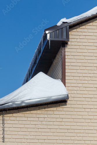 Принти на полотні Snow rests on a house roofline under clear blue sky