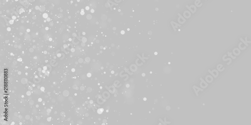 Floating white bokeh orbs create a scattered particle effect. The circles vary in size and opacity across a dark background. This glowing pattern mimics dust or snow for creative overlays.