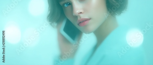 Intimate portrait of a young woman engaged in conversation on a mobile device with a blurred dreamy backdrop